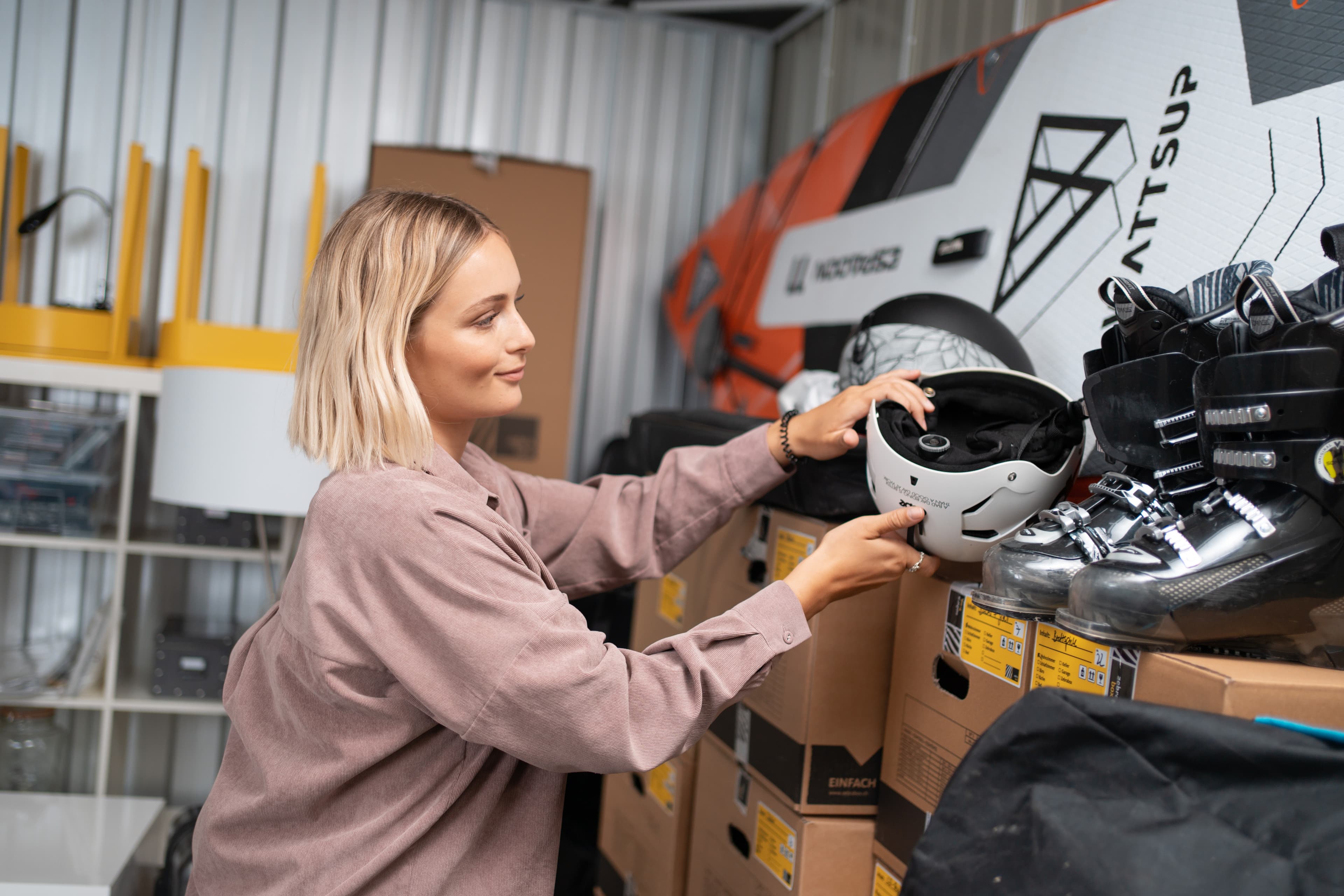 Eine junge Frau verstaut einen Skihelm im Lagerraum von Zebrabox.