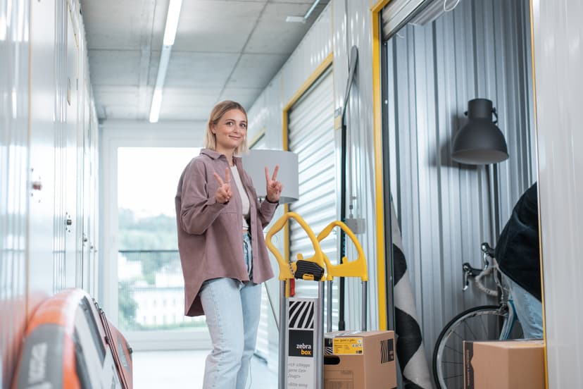 A young woman is standing in front of her Zebrabox storage unit and smiling at the camera.