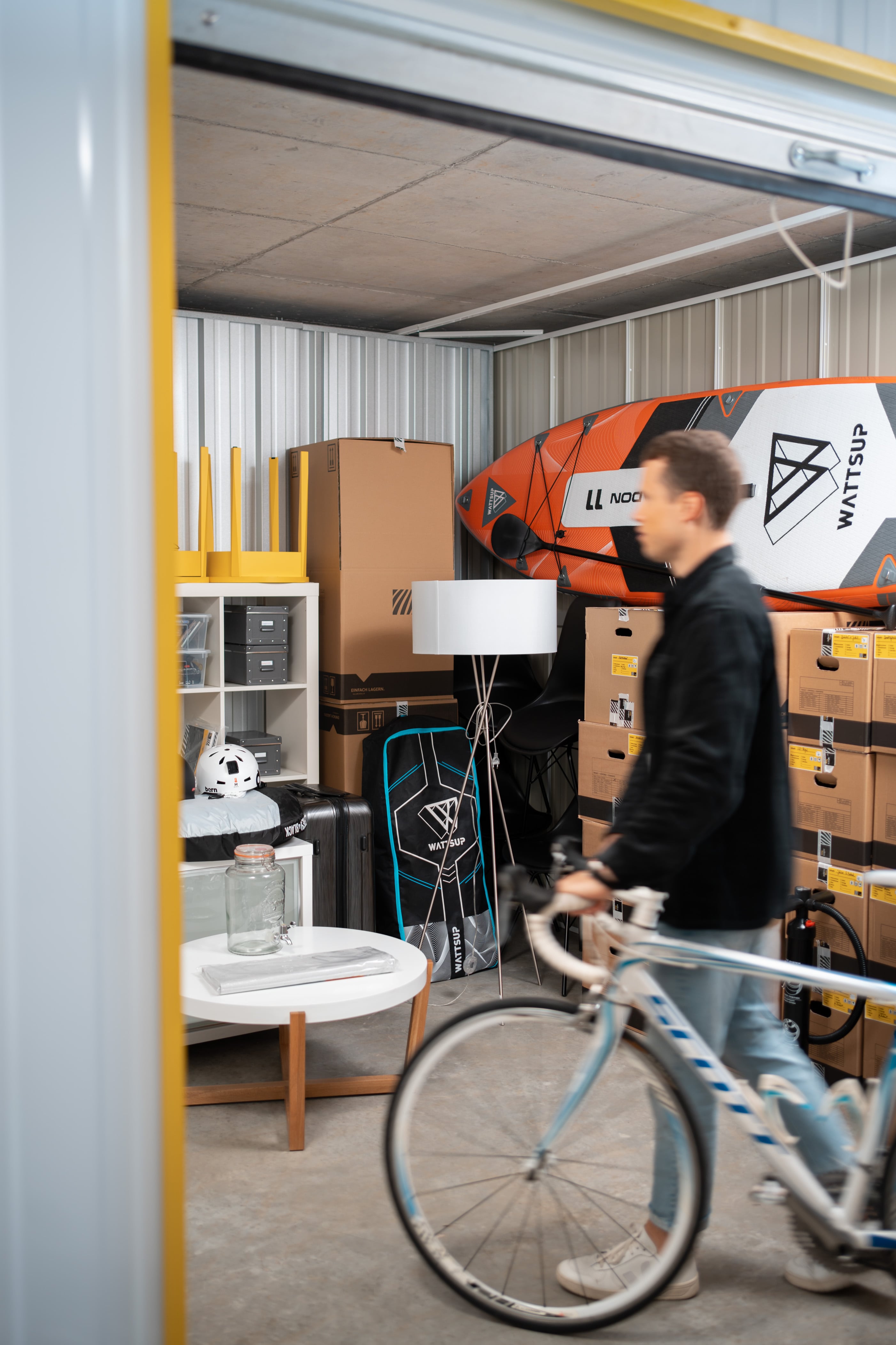 A young man is pushing his bicycle next to him and is walking into his Zebrabox storage unit.