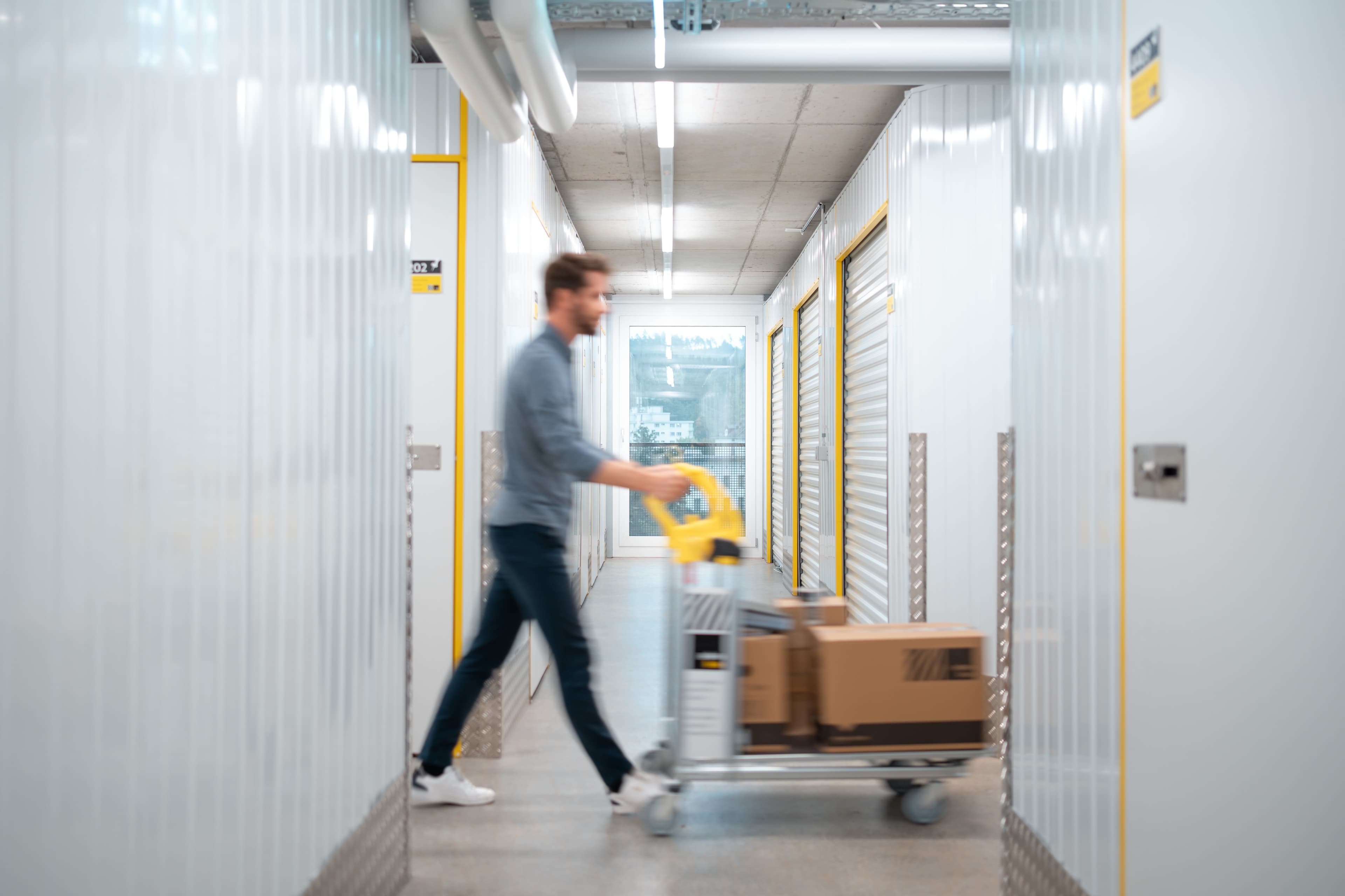Ein Mann läuft mit Rollwagen durch die Lagerhalle der Zebrabox.