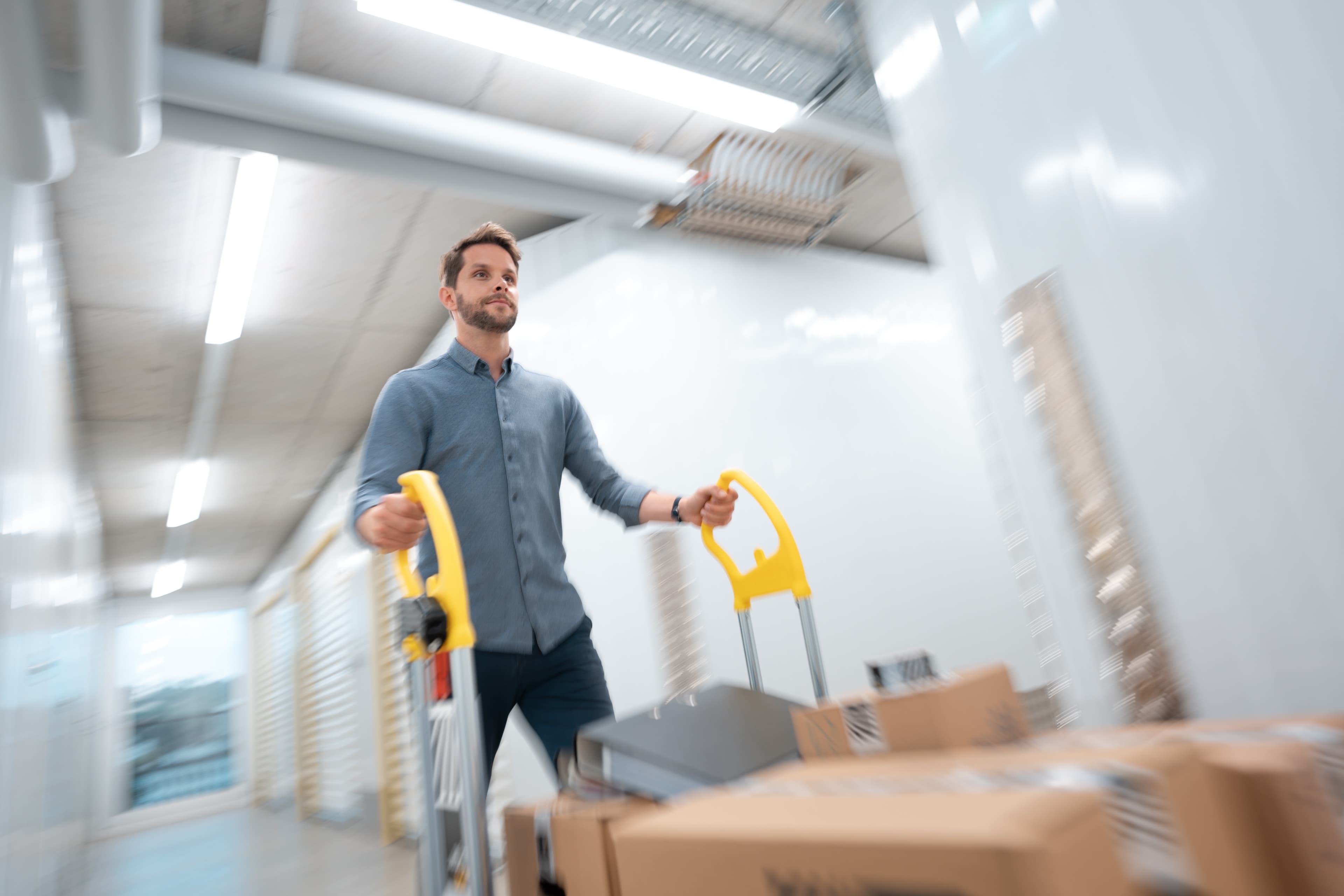 A man is pushing a trolley with moving boxes through the Zebrabox warehouse.