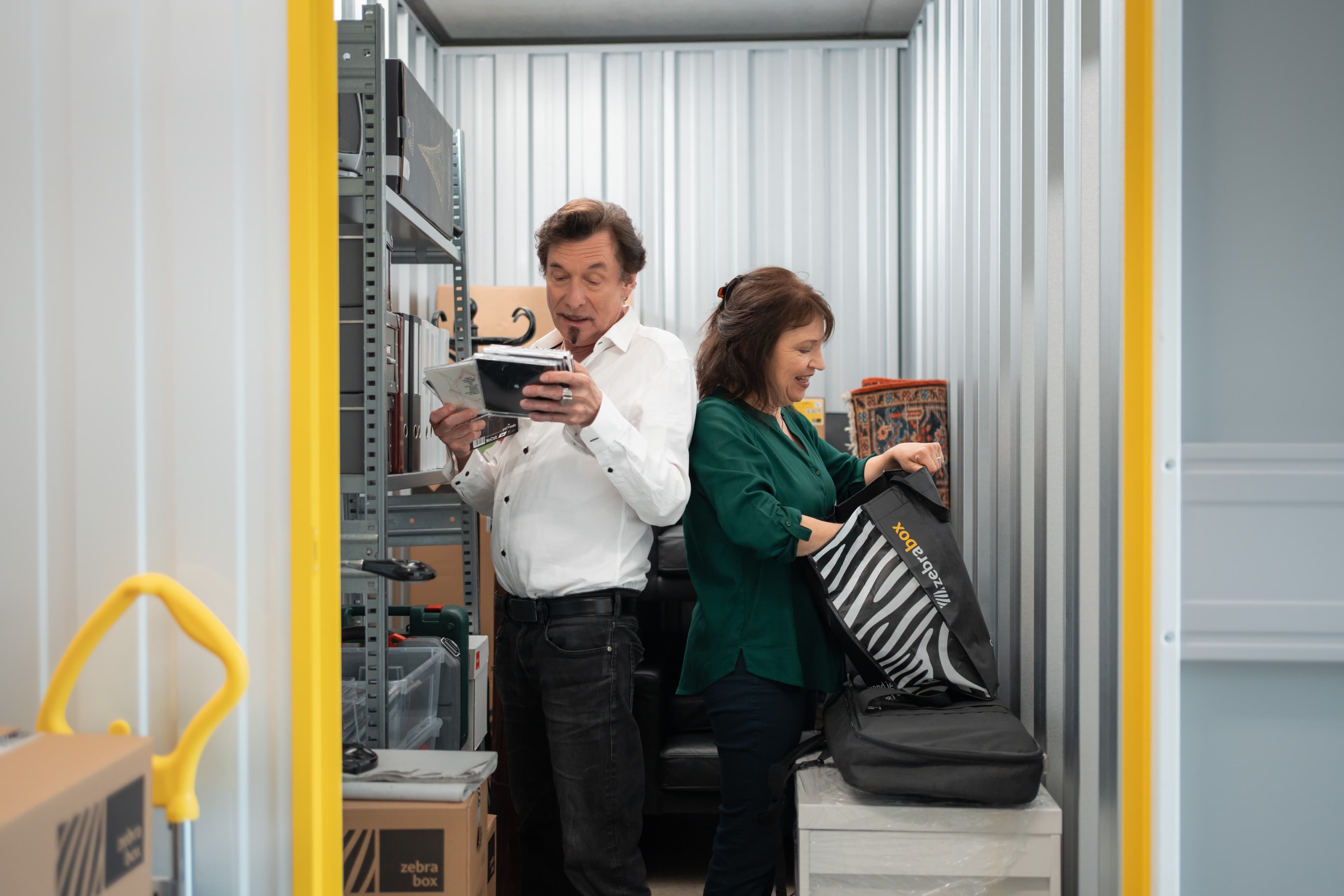 Un couple âgé se tient dos à dos et regarde les objets rangés dans leur espace de stockage chez Zebrabox.