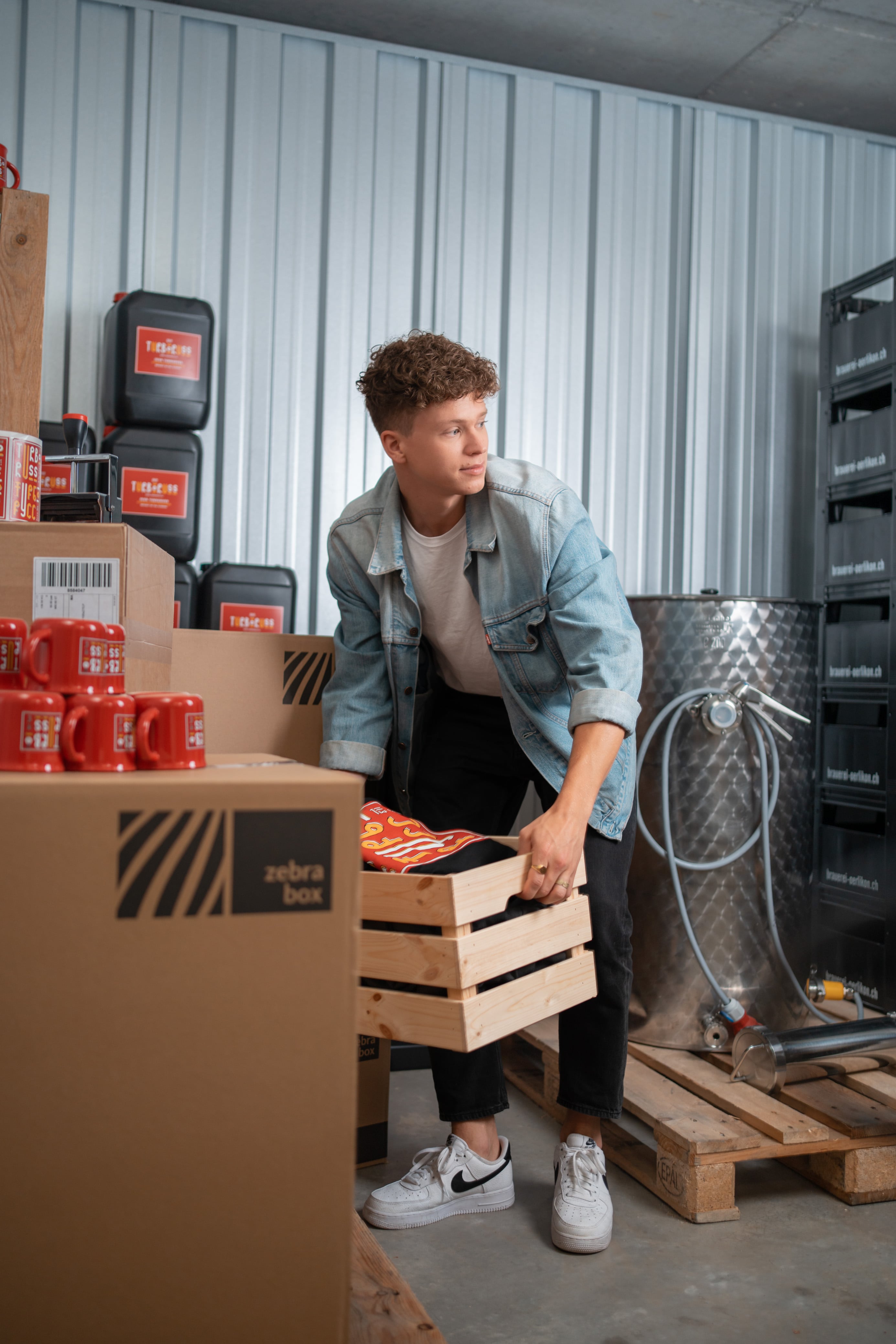 Un homme porte une caisse en bois et la place dans l'espace de stockage de Zebrabox.