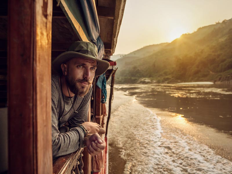 Ein Mann fährt auf einem Flussboot während Sonnenuntergang
